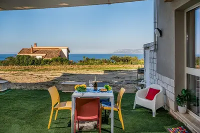 a table and chairs on a patio with a view of the ocean at Apt Perterrepermari a 2 Km Da Riserva Dello Zingaro in Scopello