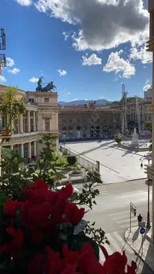 a view of a building with red flowers in the foreground at Da Marlà al Politeama in Palermo