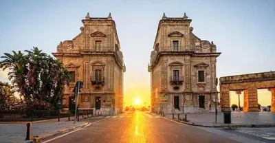 an old building on a street with the sunset in the background at LE CAMERE AL CASSARO in Palermo
