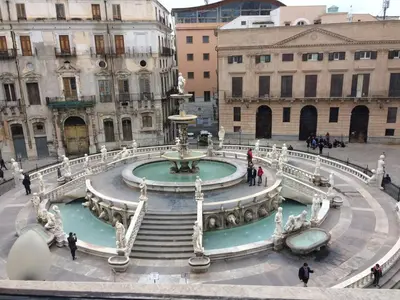 a fountain in a city with people walking around it at Teatro Apartments Giardino Inglese in Palermo