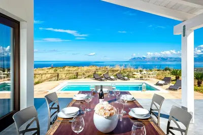 a dining room with a table and a view of the ocean at Villa Monica in Scopello