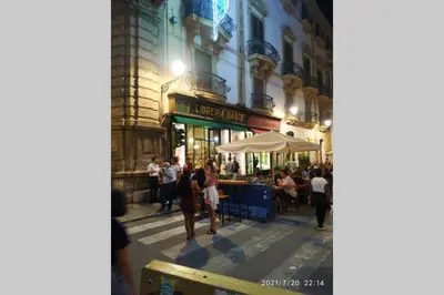 a group of people standing in a street at night at Fra la città storica e quella ottocentesca in Palermo