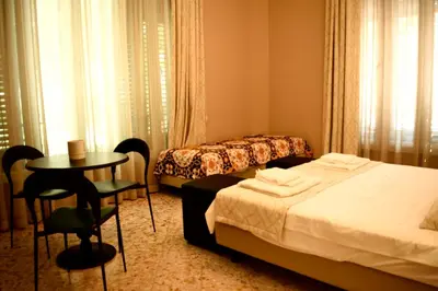 a hotel room with two beds and a table and chairs at Due Cani in Palermo