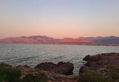 a large body of water with red mountains in the background at Luxury Villa just 50 mt from the beach, 10 minutes from the airport in Carini