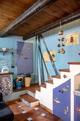 a living room with stairs and a blue wall at Nassa Apartment in Trappeto