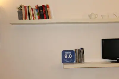 a shelf with a tv and a clock and books at Home Resuttano in Palermo