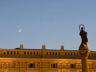 a statue in front of a building with the moon in the sky at FraLePorte Vintage Apartment in Palermo