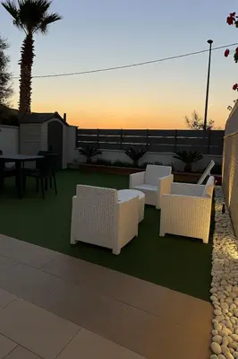 a patio with white chairs and a table and a palm tree at AR Palace Hotel - Palermo in Isola delle Femmine
