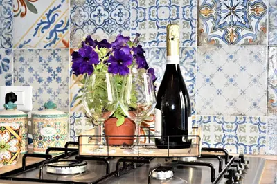 a bottle of wine and two glasses on a stove at Pozzo Antico Apartments in San Vito lo Capo