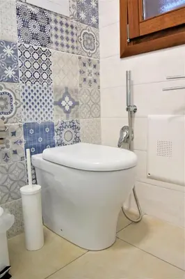 a white toilet in a bathroom with tiles at Pozzo Antico Apartments in San Vito lo Capo