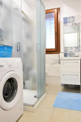 a washing machine in a bathroom with a shower at Pozzo Antico Apartments in San Vito lo Capo