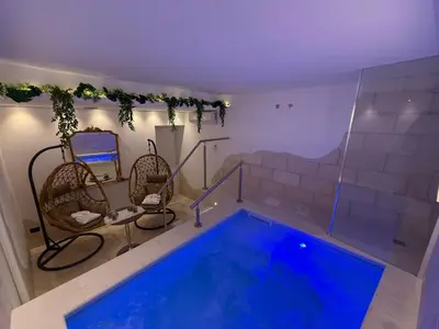 a swimming pool in a room with two chairs next to at Dimora Palermo with private pool in Palermo