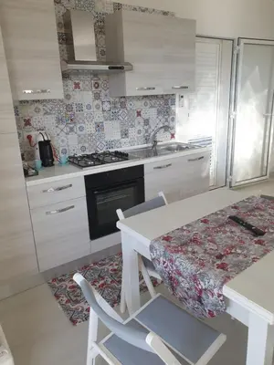 a kitchen with white cabinets and a table with chairs at CASA DEL SOLE in Alcamo