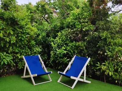 two blue and white chairs sitting on the grass at Sul mare con spiaggetta privata vicino a Cefalù. in Buonfornello