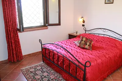 a bedroom with a red bed and a window at Casale Orioles in Torretta