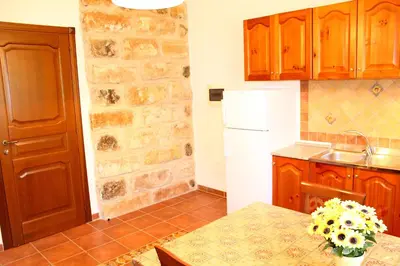 a kitchen with a table and a white refrigerator at Casale Orioles in Torretta