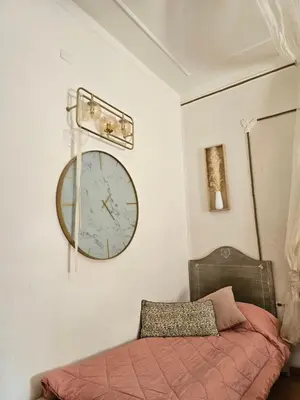 a clock hanging on a wall next to a bed at Casale D' Or in Palermo