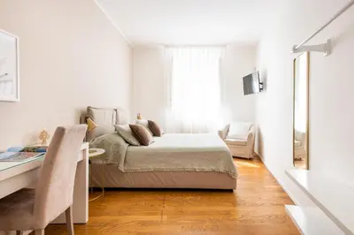 a white room with a bed and a desk at Moncada Suites & Apartments in Palermo