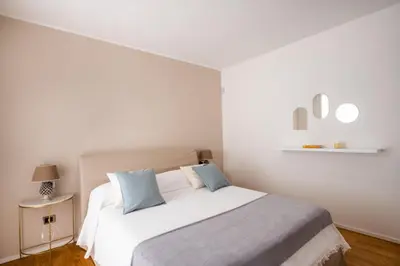 a white bedroom with a large bed with blue pillows at Moncada Suites & Apartments in Palermo