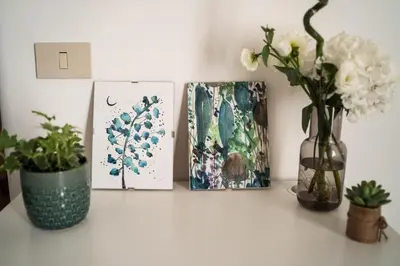 a shelf with paintings and a vase of flowers and cards at Ai Giudici in Palermo