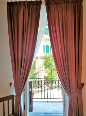 a window with red curtains looking out onto a balcony at Ai Giudici in Palermo