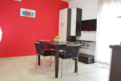 a dining room with a red wall and a table and chairs at Case Vacanze Anni 20 in Bagheria