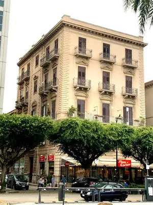 a large white building with cars parked in front of it at Suite Dreams Politeama in Palermo