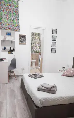 a bedroom with two beds and a desk and a bathroom at Rosina's flat in Palermo