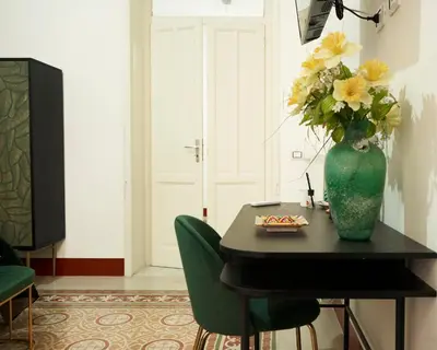 a vase with yellow flowers on a table with chairs at Ballarò Guest House in Palermo