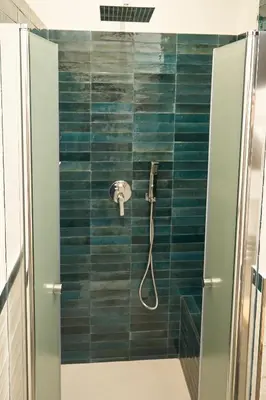 a bathroom with a shower with blue tiles at Ballarò Guest House in Palermo