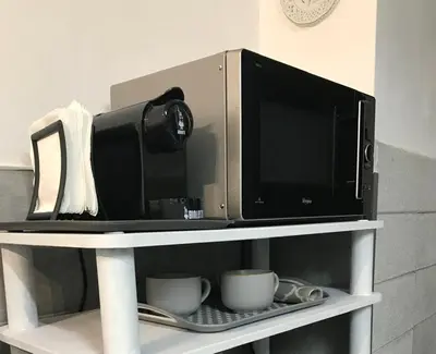 a microwave sitting on top of a shelf with cups at La Casetta Paternò “Nel Cuore Pulsante di Palermo” in Palermo