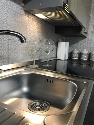 a stainless steel kitchen sink with two wine glasses at La Casetta Paternò “Nel Cuore Pulsante di Palermo” in Palermo