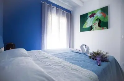 a bedroom with a bed with blue walls and a window at Sciabika Edificio Flowers in Castellammare del Golfo