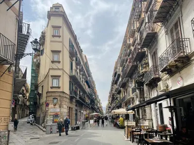 a group of people walking down a street between buildings at Parlamento Apartment - Esclusivo 120mq centro storico Palermo in Palermo