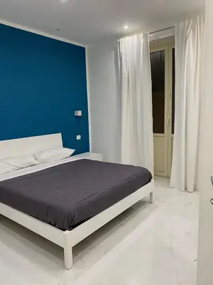 a bedroom with a large bed with a blue wall at Vittorio Emanuele & Quattro Canti Suite Palermo in Palermo