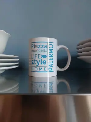 a coffee cup sitting on a table with plates and utensils at Piazza Mondello Lifestyle Home Palermo in Mondello