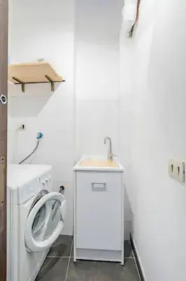 a white bathroom with a sink and a washing machine at Tavola tonda apartament in Palermo
