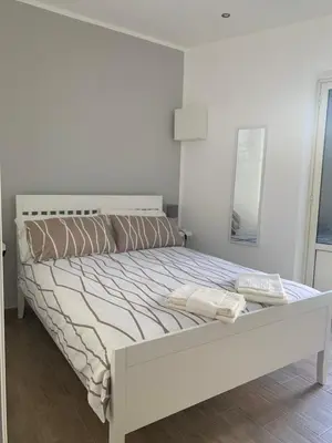 a white bedroom with a bed with a white headboard at San Saverio Home in Palermo