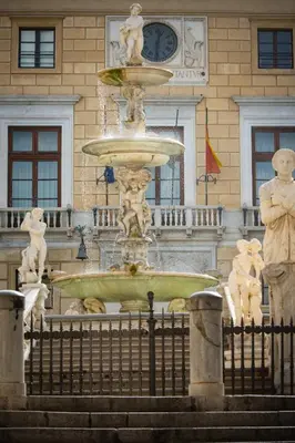a fountain in front of a building with a clock at San Saverio Home in Palermo