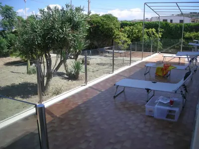 a patio with two picnic tables and a fence at Villa On The Beach Spiaggia Plaia in Castellammare del Golfo