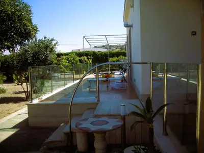 a balcony of a house with a table and a pool at Villa On The Beach Spiaggia Plaia in Castellammare del Golfo
