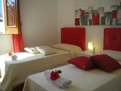 three beds in a room with red and white at Villa On The Beach Spiaggia Plaia in Castellammare del Golfo