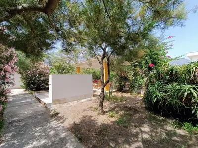 a white sign in a yard next to a tree at Villa On The Beach Spiaggia Plaia in Castellammare del Golfo