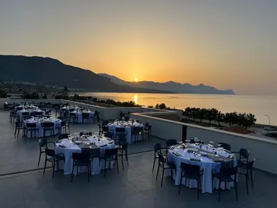 a room with tables and chairs with a view of the ocean at Resort La Battigia Beach & Spa in Alcamo Marina