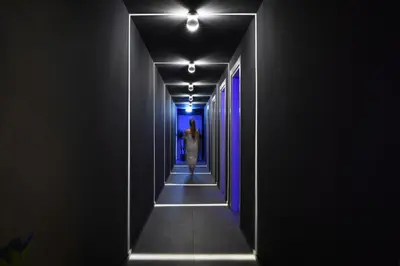 a woman walking down a hallway with blue lights at Resort La Battigia Beach & Spa in Alcamo Marina