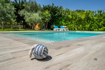 a ball on a wooden floor next to a swimming pool at VILLA HIBISCUS in Castellammare del Golfo
