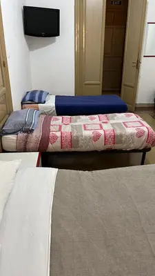 two beds in a room with a tv on the wall at Manzoni rooms in Palermo