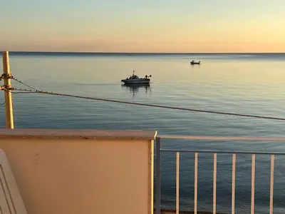 two boats floating in the water at sunset at Villa GLORIA intero alloggio sulla spiaggia 8 posti letto 15 minuti da Palermo e 35 da Cefalu in Casteldaccia