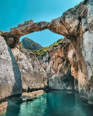 an arch in the rocks in a body of water at Villa GLORIA intero alloggio sulla spiaggia 8 posti letto 15 minuti da Palermo e 35 da Cefalu in Casteldaccia