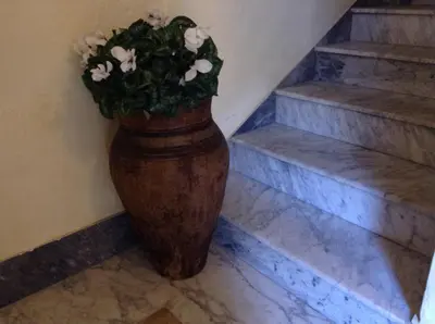 a large vase with flowers in it next to stairs at Verdi Apartment in Castellammare del Golfo